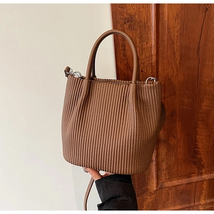 Detail of pleated brown bucket bag with smooth round handle and silver metal hardware