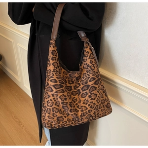 Detail view of large leopard print hobo bag with dark brown leather straps on a model