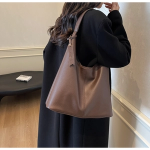 Close-up of litchi grain leather texture and hanging tag on a large brown tote bag