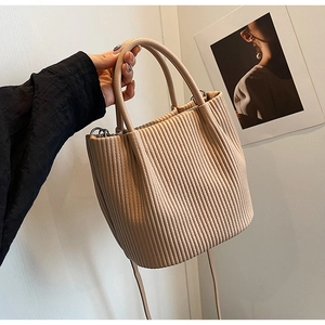 Detailed view of beige pleated bucket bag texture with soft leather carry handle