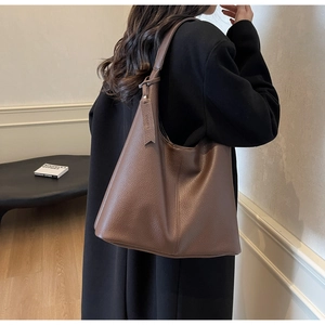 Close-up of brown pebbled leather hobo bag with thick shoulder strap and minimalist charm