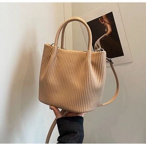 Detailed close-up of a beige pleated bucket bag with chic textures and shoulder strap