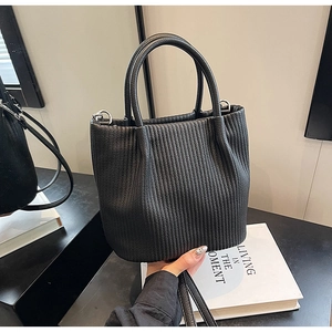 Detailed close-up of a black pleated bucket bag showing vertical texture and dual handles