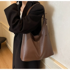 Close-up of a large dark brown tote bag in premium pebble-grain leather with visible seams