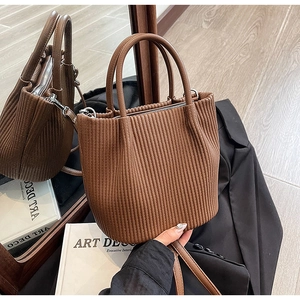 Detailed close-up of brown pleated bucket bag with lychee grain texture and silver hardware