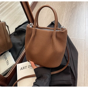 Detail of pleated brown corduroy bucket bag texture with adjustable strap and top handles