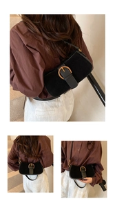 Detail of black suede underarm bag with elegant gold ring buckle on vintage baguette style