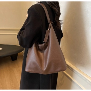 Detail of large brown pebble leather tote bag with wide shoulder strap on model back