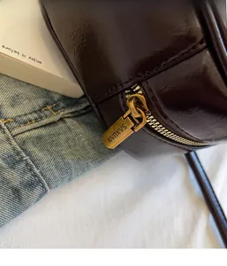 Detail of vintage brass zipper on high-quality dark brown oiled leather shoulder bag