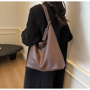 Detail of dark brown pebble leather hobo tote with decorative tag and shoulder strap