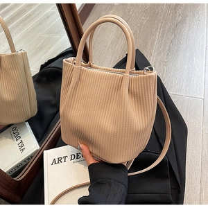 Detailed view of beige pleated bucket bag texture with top handles and shoulder strap
