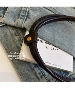 Close-up of deep brown shoulder strap with golden snap button and fine stitching