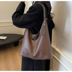 Macro detail of dark brown litchi leather texture on a spacious tote bag with shoulder strap