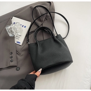 Close-up of black pleated texture on luxury bucket bag with smooth round base and strap