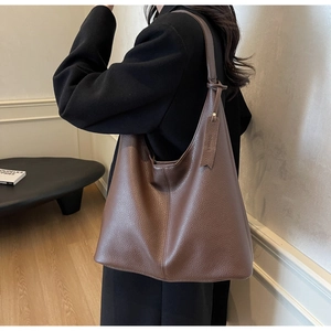 Detail view of large brown lychee grain leather hobo bag with matching tag on model