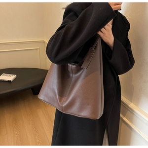 Close-up of deep brown lychee grain leather tote bag showing texture and shoulder strap