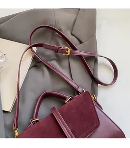 Detail of adjustable leather strap and polished gold hardware on a wine red bag