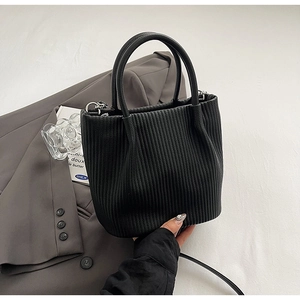 Detailed macro view of the black pleated bucket bag with silver D-ring and elegant handle