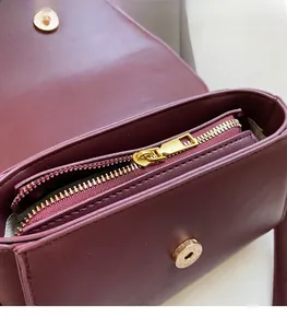 Detail of smooth gold zipper and magnetic closure on burgundy suede leather handbag