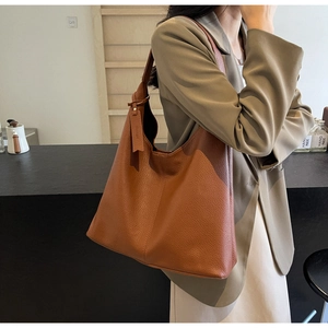 Detailed side view of large brown pebble leather tote bag during casual commuting