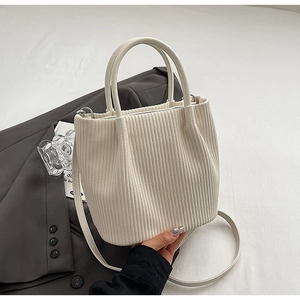 Detail of cream pleated bucket bag with round handle and detachable shoulder strap