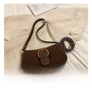 Detail of dark brown leather handbag featuring suede panels and golden horseshoe buckle