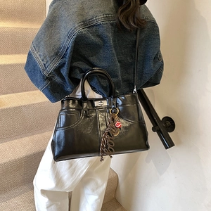 Large black patent leather tote bag with decorative stitching and silver twist lock