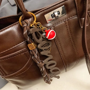 Brown leather tote bag with stylish textured pebble grain and designer bag charm accents