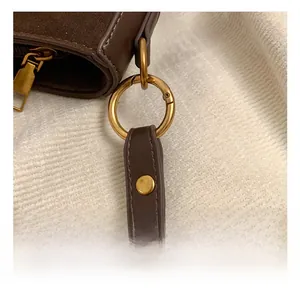 Detail shot of vintage dark brown suede bag featuring a round golden metal hook and hardware