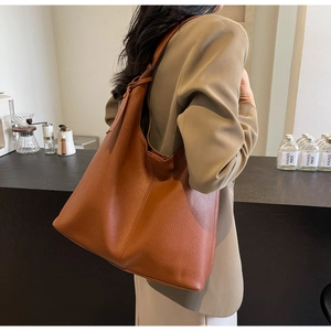 Detail of caramel brown pebbled leather tote bag with soft texture and spacious design