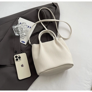 Close-up of white pleated bucket bag texture with leather handle and slim shoulder strap