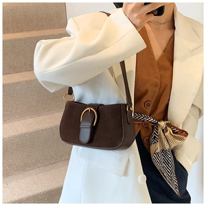 Close-up of dark brown suede shoulder bag with gold buckle on white staircase