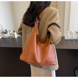 Detailed view of brown lychee grain leather tote bag with decorative brand tag