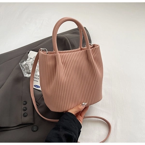 Detail of pink pleated bucket bag with round handles and textured faux leather surface