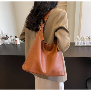 Detail of the brown lychee grain leather tote bag with a knotted strap and leather tag