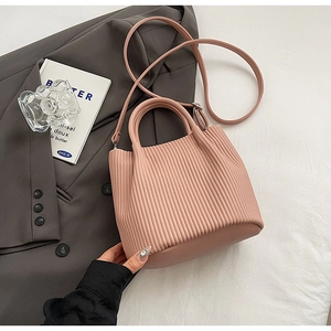 Detailed close-up of pink pleated bucket bag on grey blazer with elegant lifestyle decor