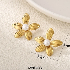 Detail of gold flower earrings with central white pearl and textured metal petals