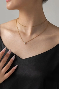 Detail of layered gold titanium steel necklace with a sparkling round diamond pendant