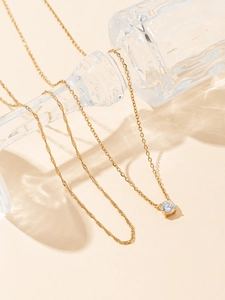 Detail of a minimalist gold necklace featuring a four-prong set round zircon pendant