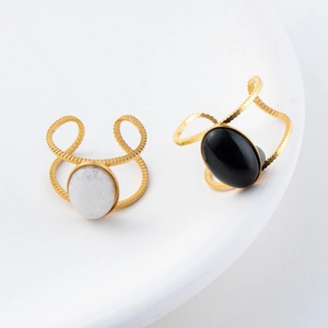 Detailed close-up of 18K gold plated oval rings with black and white drip oil stones