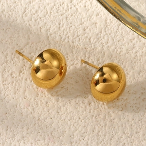 Macro shot of polished gold-tone dome stud earrings on a textured off-white background