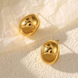 Macro view of gold bean stud earrings with high-polished mirror finish and organic texture