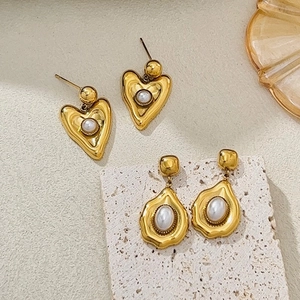 Détail de boucles d'oreilles vintage en cœur et goutte d'eau avec perles et finition or mat