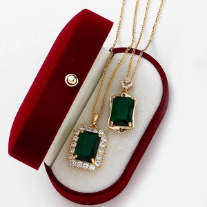 Detail of emerald green rectangular pendants in gold finish with velvet box