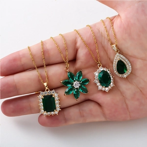 Close-up of four gold necklaces with emerald-cut green gemstones in various elegant shapes