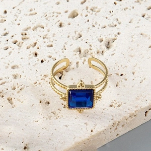 Vintage adjustable gold ring with square deep blue gemstone on a textured stone base