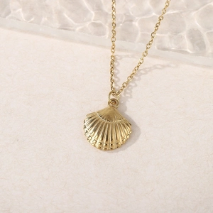 Close-up of golden shell pendant necklace with radial texture on a soft rippled background