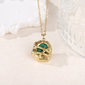Macro shot of 18k gold plated necklace with green malachite stone in hollow cage pendant