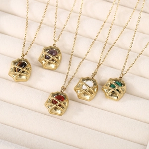 Macro view of gold plated necklaces with colorful natural stone pendants on beige tray