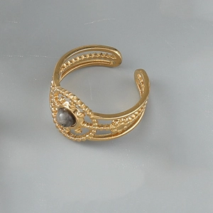 Détail d'une bague égyptienne dorée multicouche avec pierre grise et filigrane